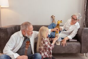 Grandmother and grandfather playing with stuffed animals with granddaughter