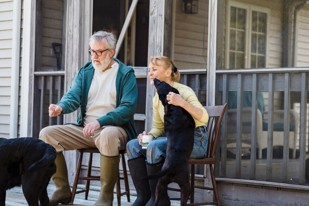Smiling homeowner over 60 holding coffee on the front porch of her home