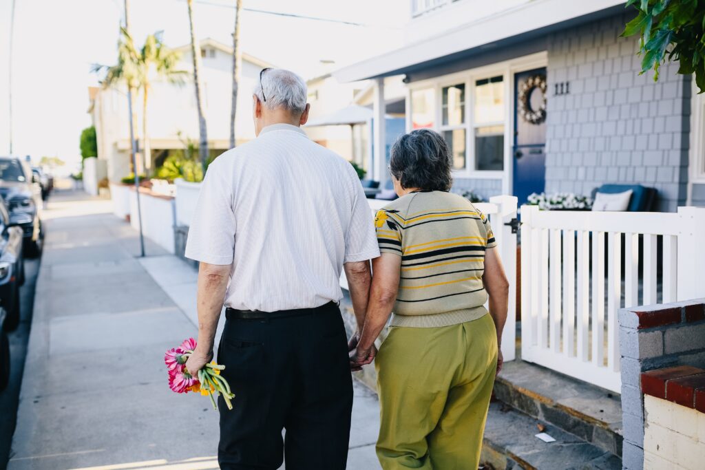 Couple walking down the sidewalk passing retirement suitable homes