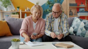 Couple over 60 reviewing capital gains tax on home sale paperwork at their kitchen table
